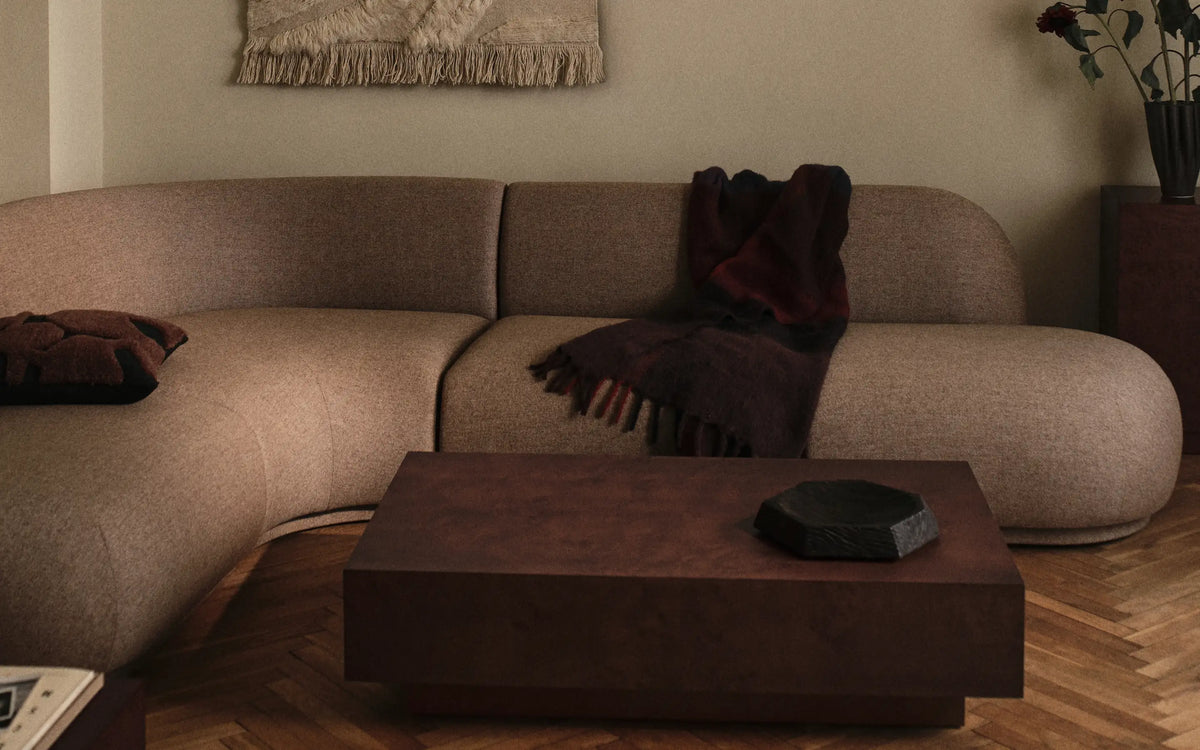 Design din egen sofa, buet modulsofa i beige med et mørkerødt plaid og et lavt rektangulært sofabord
