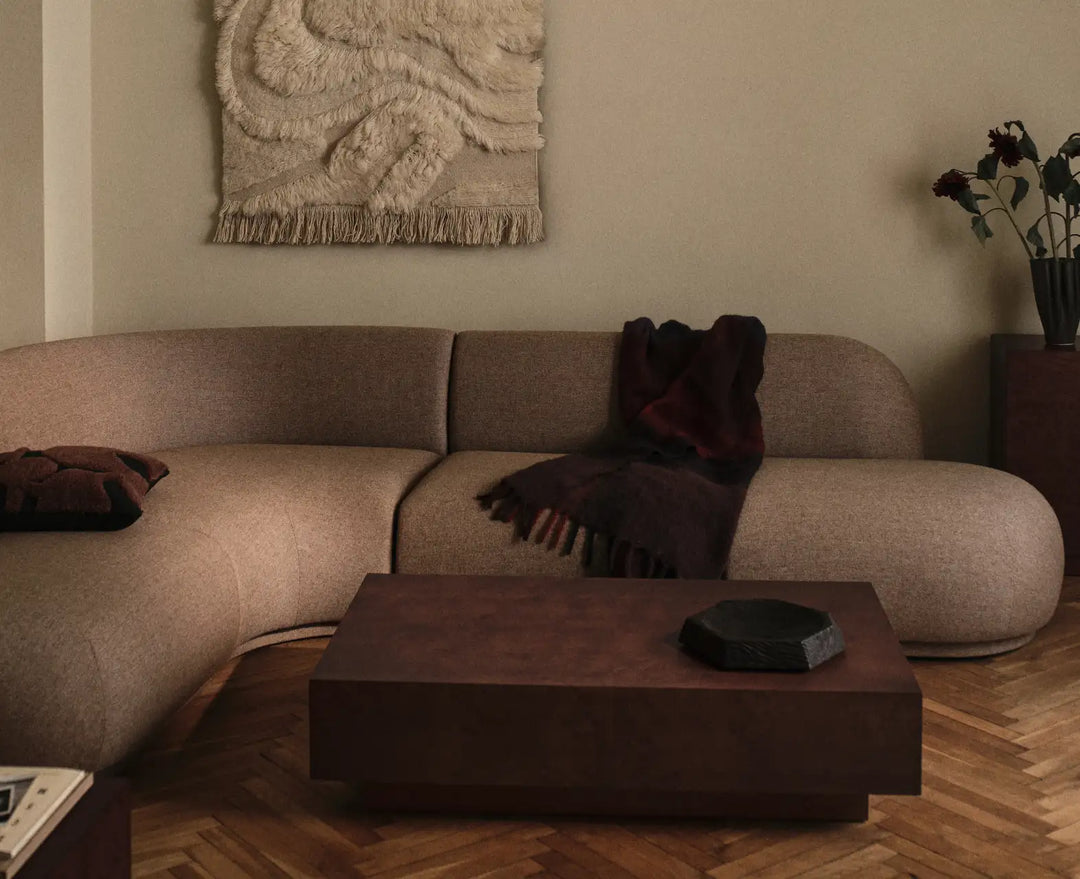 Design din egen sofa, buet modulsofa i beige med et mørkerødt plaid og et lavt rektangulært sofabord