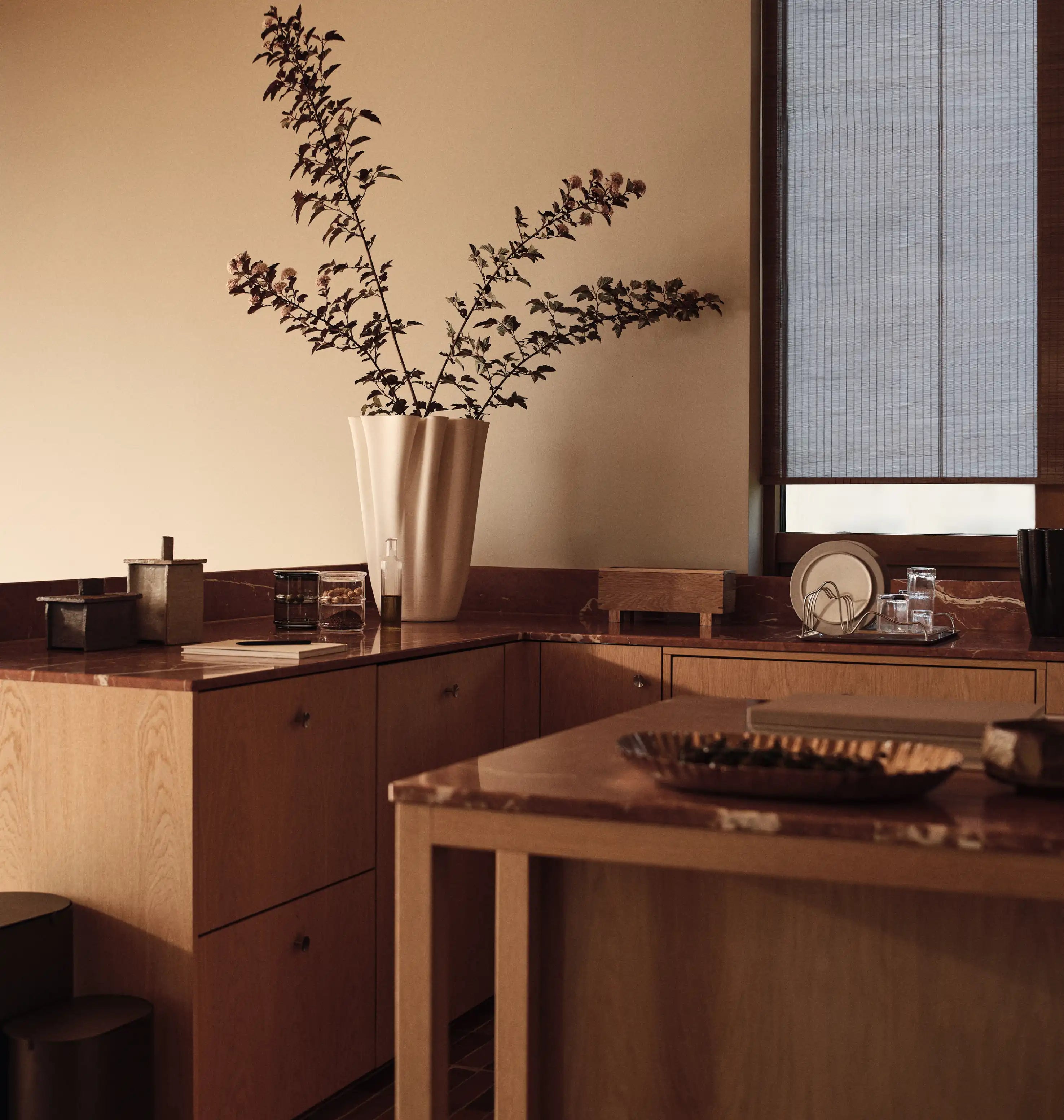 Køkkenet, køkken med rødårede bordplader, riflet vase med grene, glas i vindueskarmen